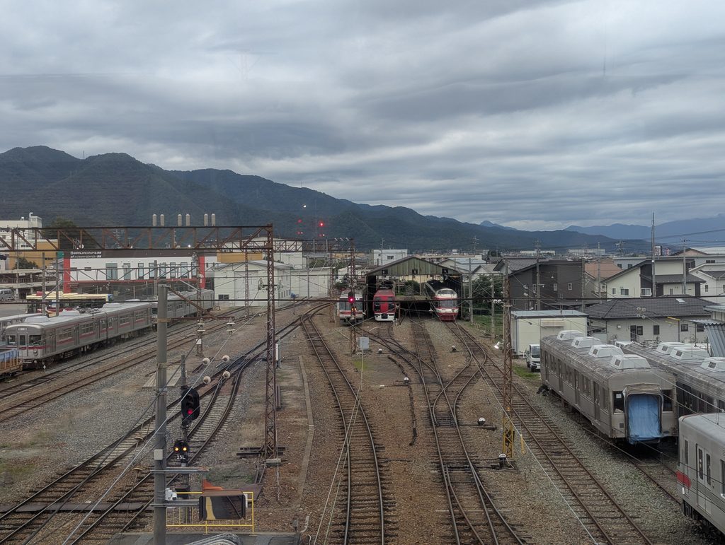 須坂駅の車両基地に並ぶ列車と、その奥の山並み