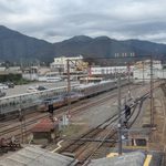 須坂駅構内に広がる線路と信号機、銀色の列車と山並み