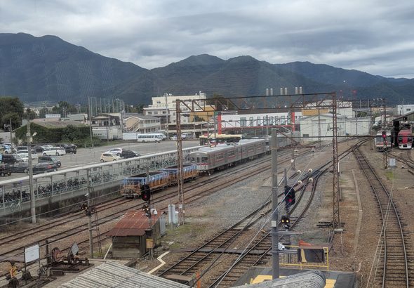 須坂駅構内に広がる線路と信号機、銀色の列車と山並み