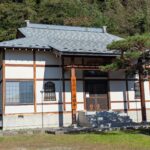 高山村・海福寺の本堂。白壁と木の柱、正面に枝を伸ばす松