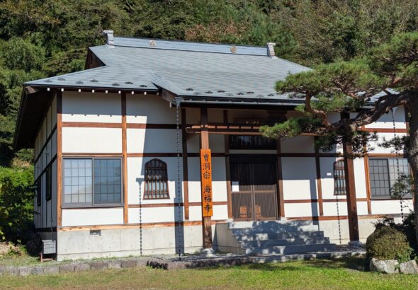 高山村・海福寺の本堂。白壁と木の柱、正面に枝を伸ばす松