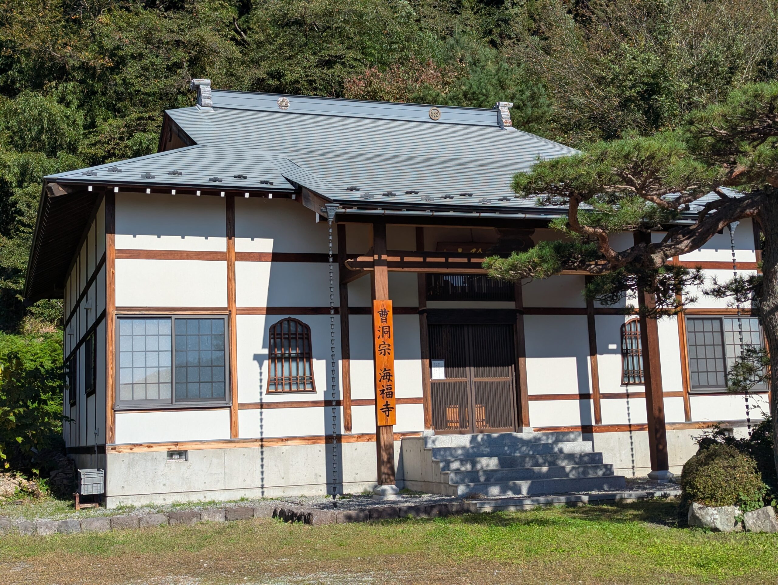 高山村・海福寺の本堂。白壁と木の柱、正面に枝を伸ばす松